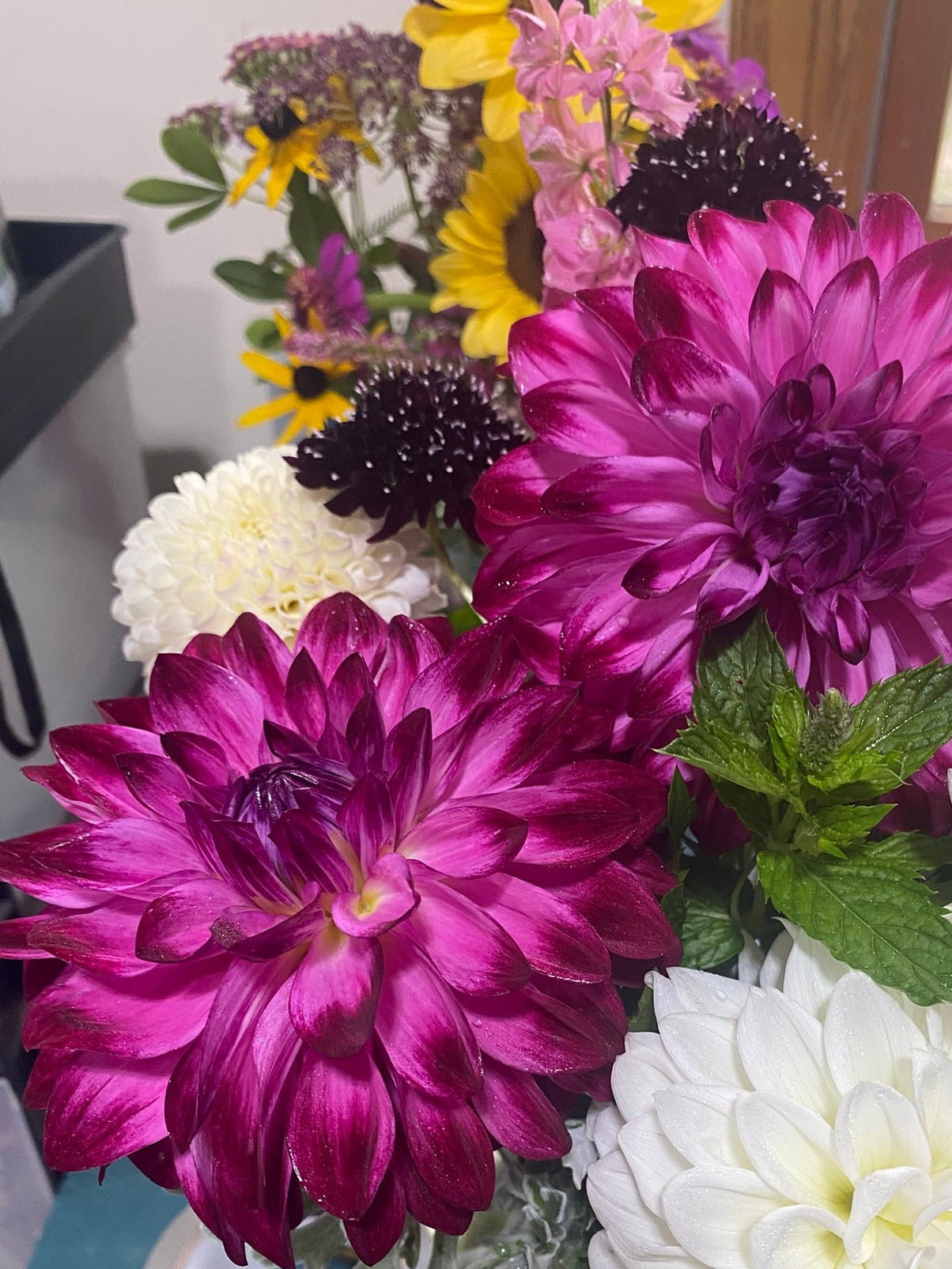 Bouquet of purple, white, and yellow flowers in a clear vase on a blue surface.